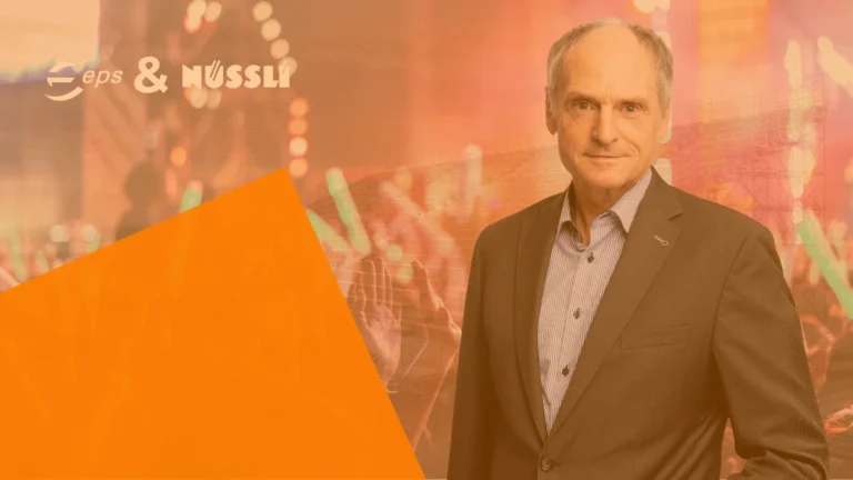Georg Keller im Vordergrund das Bild im Hintergrund zeigt eine Bühne und das Publikum davor.